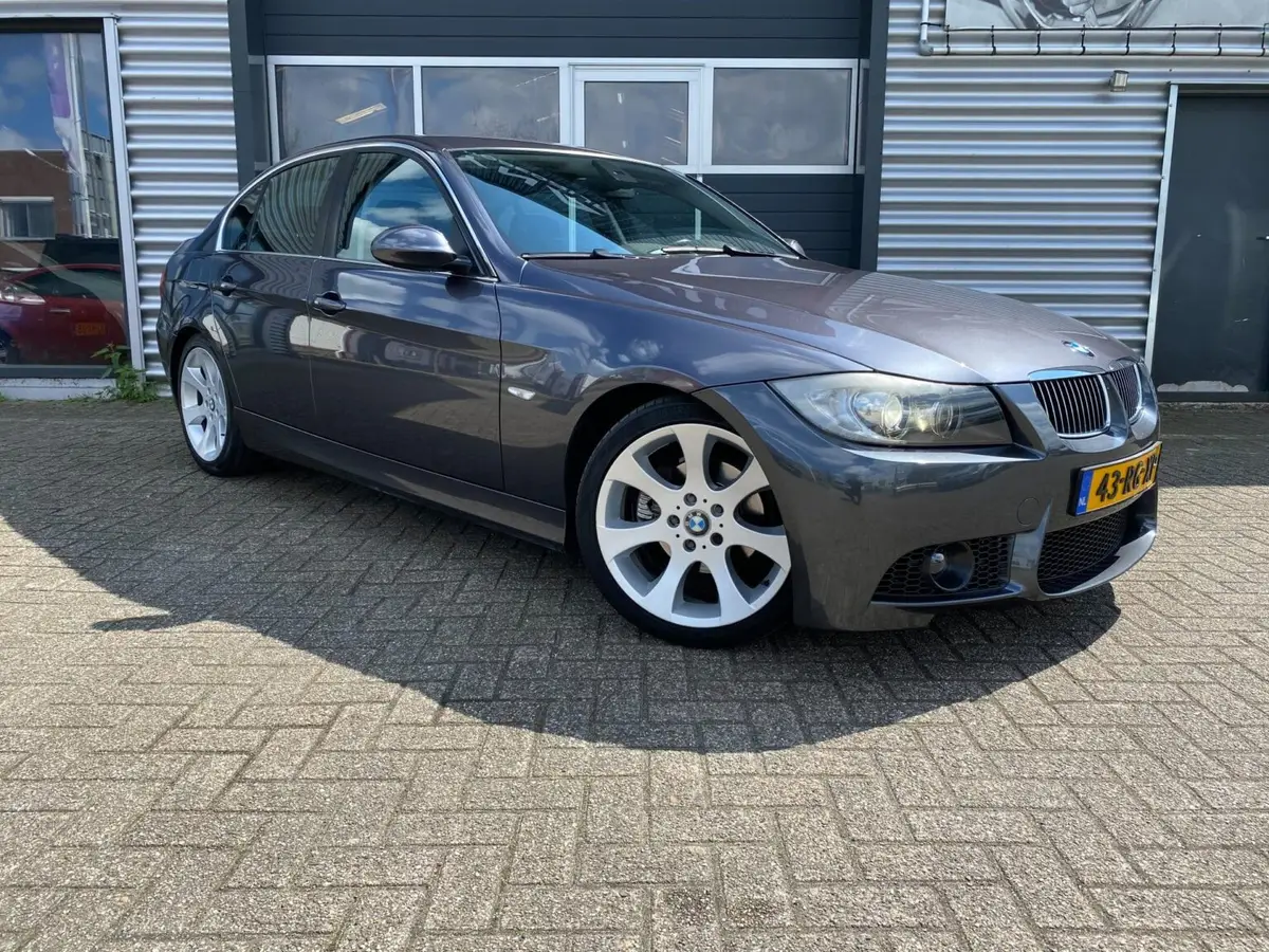 Grijze BMW 3-serie voor het pand van Autobedrijf Dyna